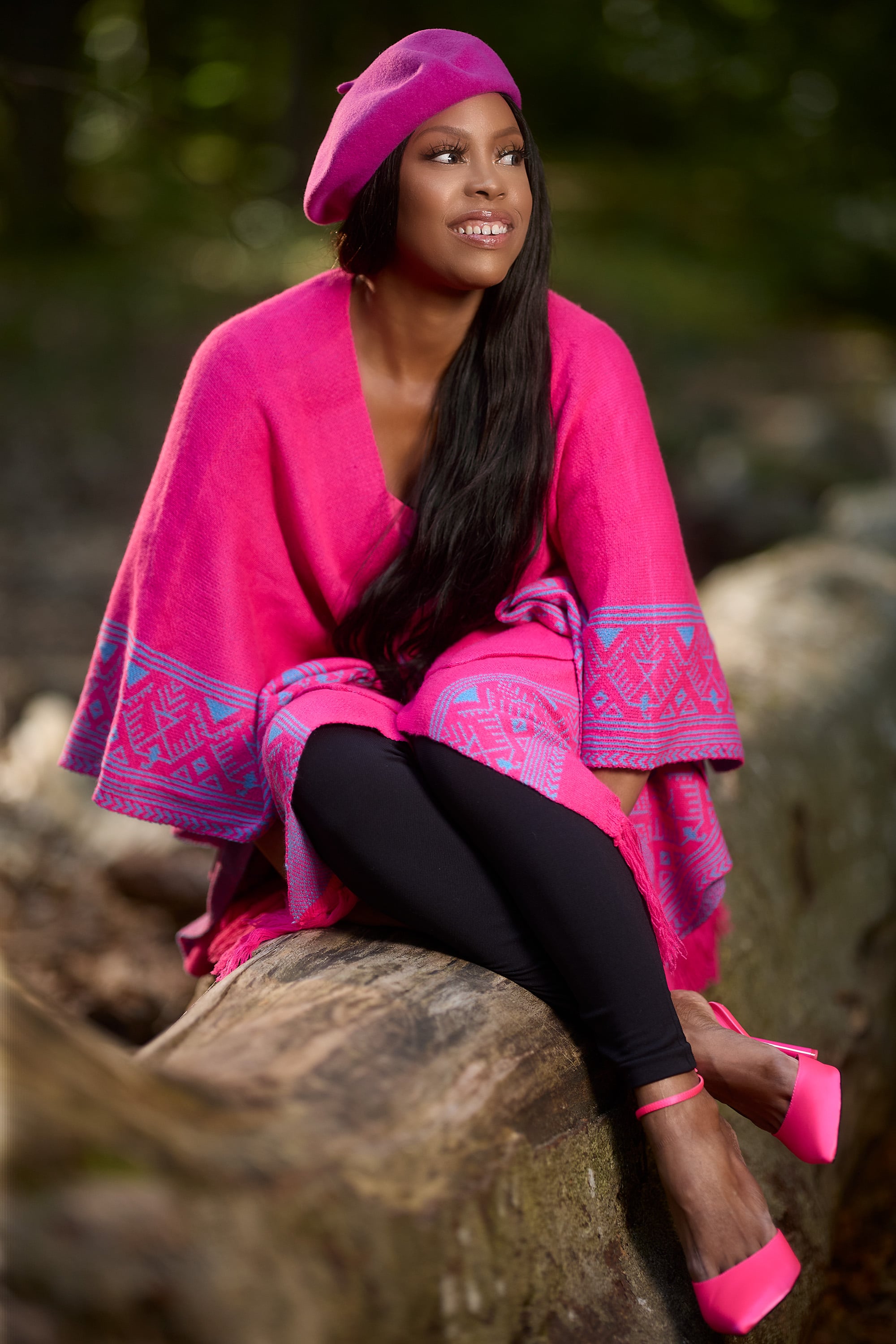 Kiralina sitting on a log with bright pink outfit hat and shoes.